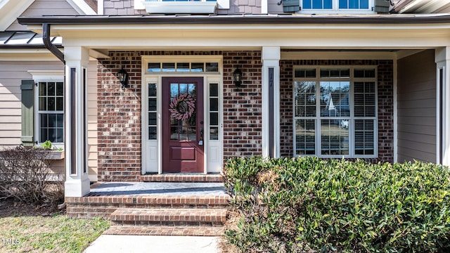 entrance to property featuring a porch and brick siding