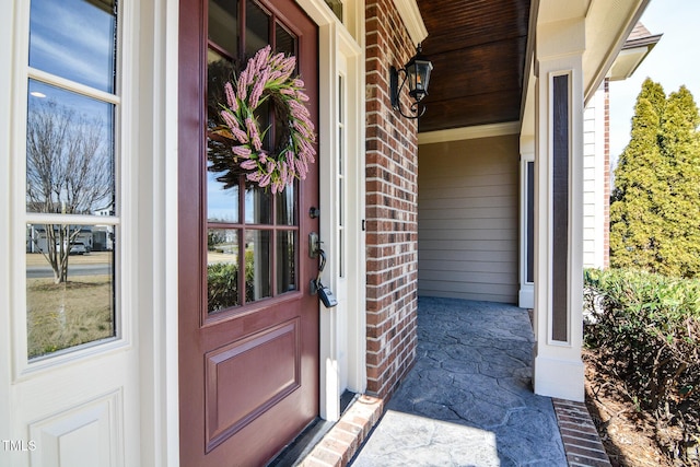 entrance to property featuring covered porch and brick siding