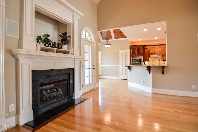 living area featuring light wood finished floors, recessed lighting, baseboards, and a high end fireplace