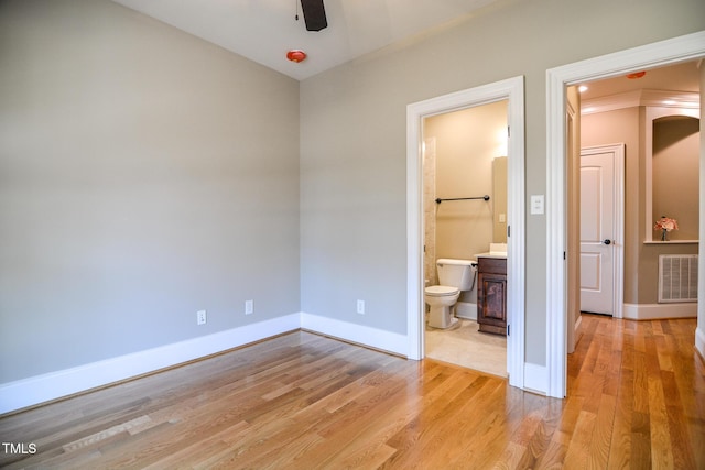 unfurnished bedroom featuring light wood-type flooring, ensuite bath, baseboards, and visible vents