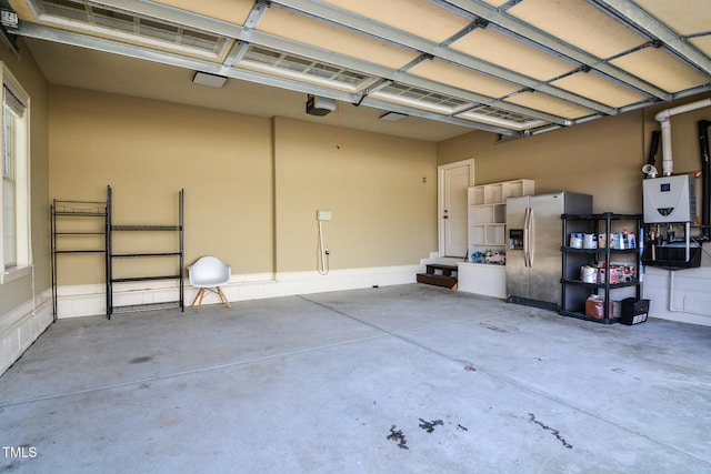 garage with a garage door opener and stainless steel fridge with ice dispenser