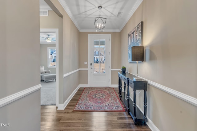 foyer featuring baseboards, wood finished floors, visible vents, and ornamental molding