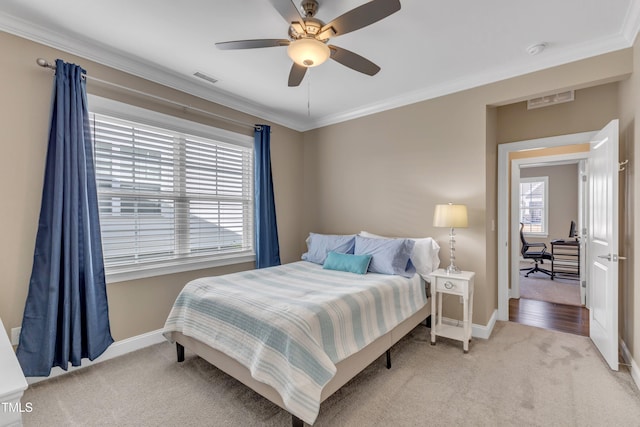 bedroom featuring crown molding, light colored carpet, visible vents, and baseboards