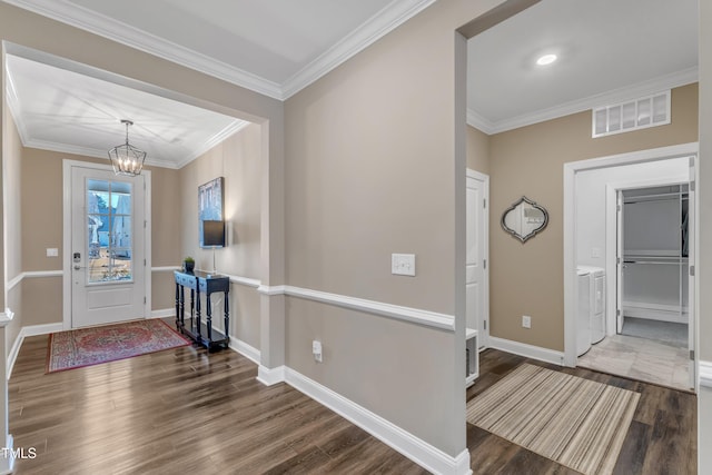 foyer featuring wood finished floors, visible vents, an inviting chandelier, separate washer and dryer, and ornamental molding