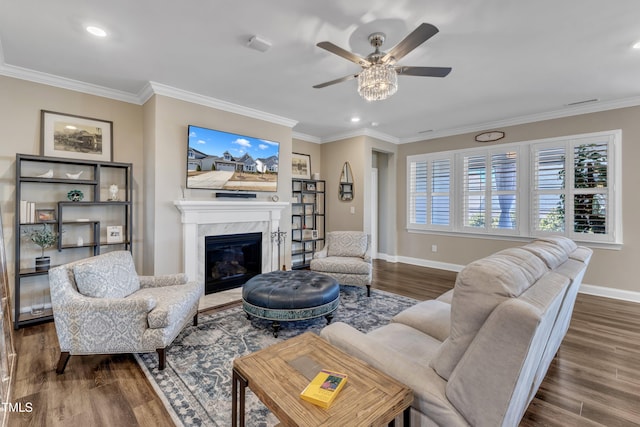 living room featuring a fireplace, crown molding, baseboards, and wood finished floors