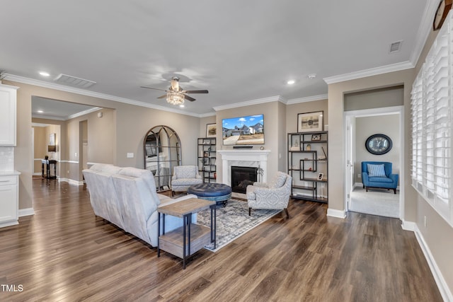 living area with visible vents, a premium fireplace, dark wood finished floors, and ornamental molding