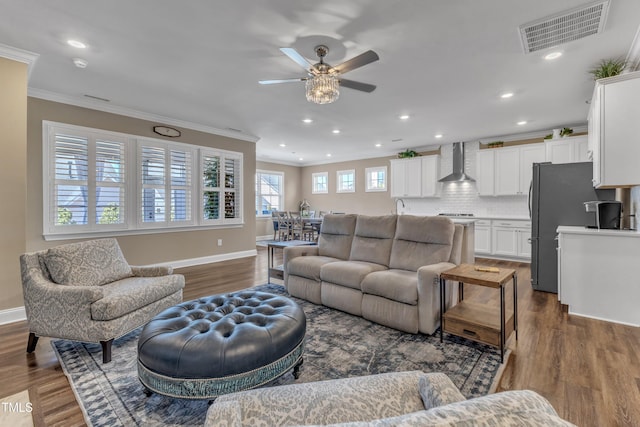 living area with visible vents, dark wood-style floors, and ornamental molding