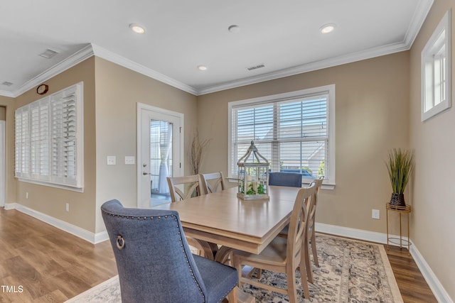 dining space with a wealth of natural light, visible vents, crown molding, and wood finished floors