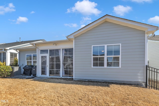 back of property with central AC unit, fence, a yard, and a sunroom