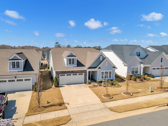 view of front of house with stone siding, a garage, a residential view, and driveway