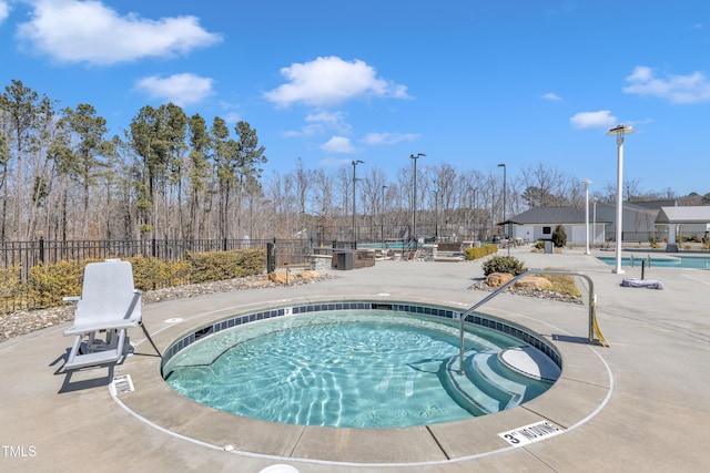 pool with a hot tub, a patio, and fence