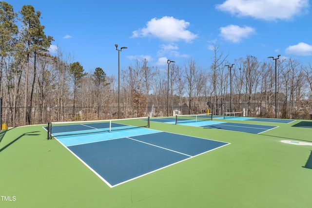 view of tennis court with community basketball court and fence