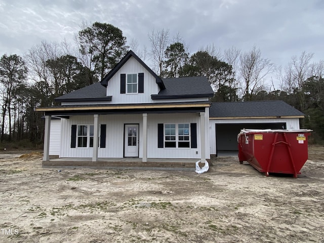 back of house with an attached garage, a shingled roof, and a porch