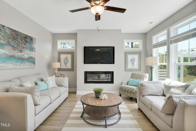 142 Oban Dr, Home, Sanford, NC 27330 - living room featuring baseboards, ceiling fan, light wood-style flooring, and a glass covered fireplace