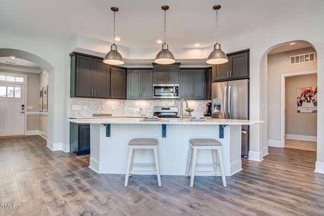 142 Oban Dr, Home, Sanford, NC 27330 - kitchen with appliances with stainless steel finishes, visible vents, light countertops, arched walkways, and backsplash
