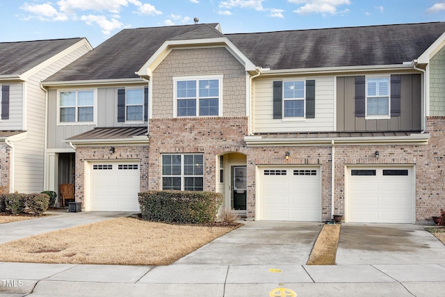 multi unit property featuring driveway, brick siding, a standing seam roof, and an attached garage