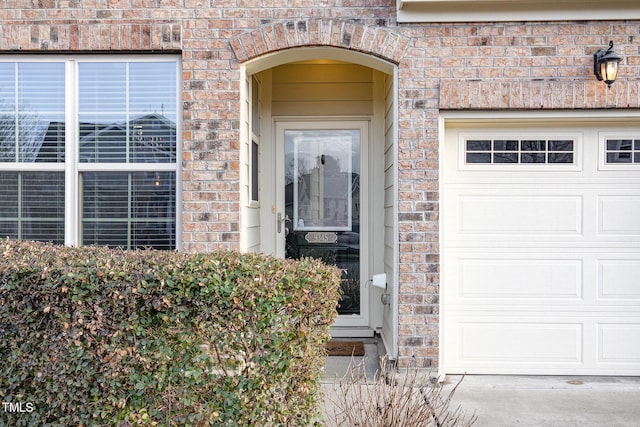 entrance to property with brick siding and an attached garage