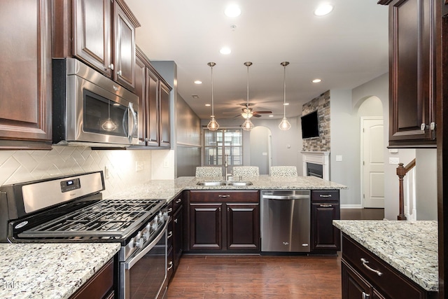 kitchen featuring arched walkways, ceiling fan, appliances with stainless steel finishes, a peninsula, and a sink