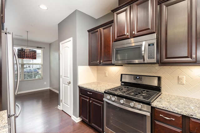 kitchen with dark wood finished floors, tasteful backsplash, appliances with stainless steel finishes, light stone countertops, and baseboards