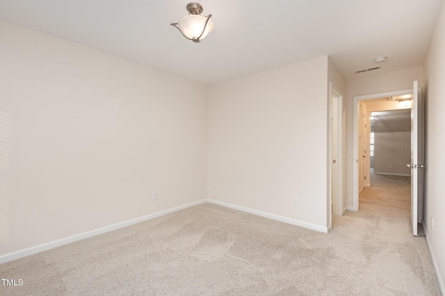 empty room featuring baseboards and light colored carpet