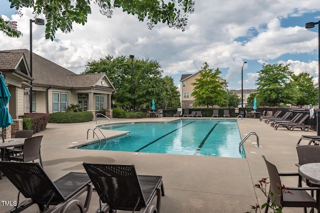 community pool with a patio area and fence