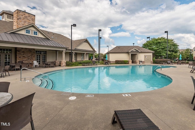 community pool with french doors and a patio area