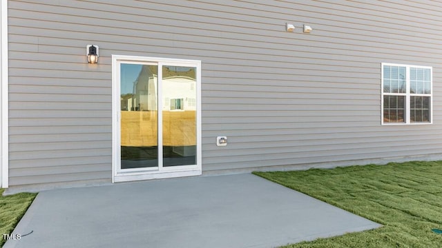 doorway to property featuring a patio and a lawn