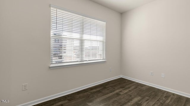 spare room with dark wood finished floors and baseboards