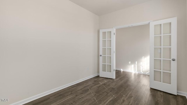 empty room with french doors, dark wood finished floors, and baseboards