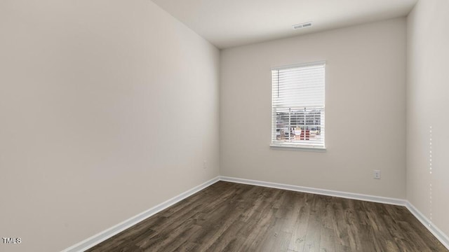 unfurnished room featuring visible vents, baseboards, and dark wood finished floors