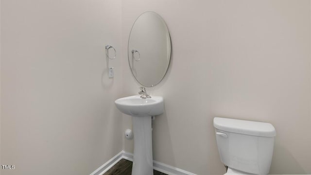 half bathroom with baseboards and toilet