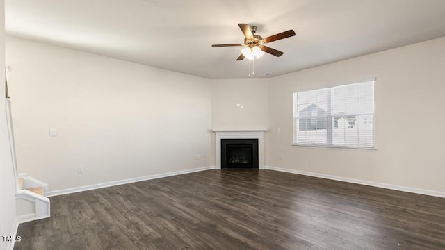 unfurnished living room featuring a fireplace, baseboards, dark wood finished floors, and a ceiling fan