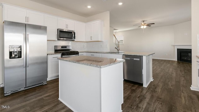 kitchen with dark wood-style floors, stainless steel appliances, a peninsula, and white cabinetry