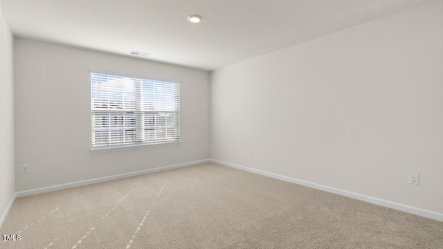 unfurnished room with baseboards and light colored carpet