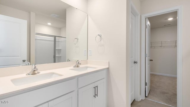 full bath with a walk in closet, a sink, baseboards, and double vanity