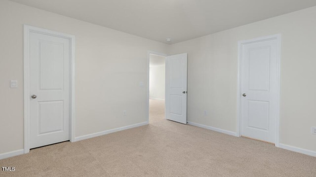 spare room featuring light carpet and baseboards