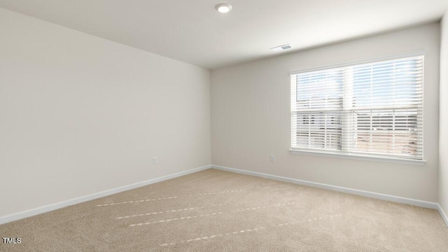 spare room featuring visible vents, baseboards, and light colored carpet