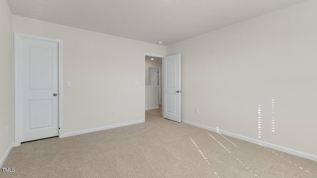 unfurnished room with baseboards and light colored carpet