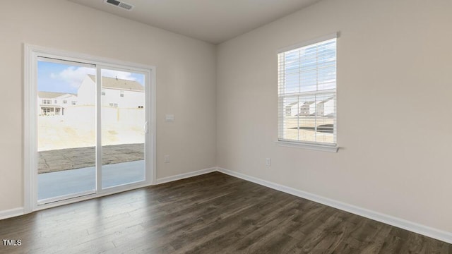 spare room featuring visible vents, baseboards, and dark wood-style flooring