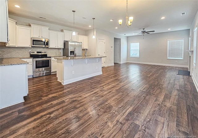 kitchen with dark wood-style floors, stainless steel appliances, tasteful backsplash, open floor plan, and ceiling fan with notable chandelier