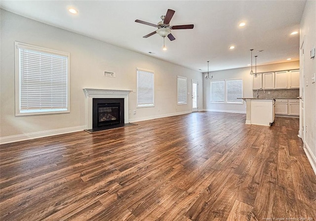 unfurnished living room featuring ceiling fan, dark wood-style flooring, a glass covered fireplace, and recessed lighting