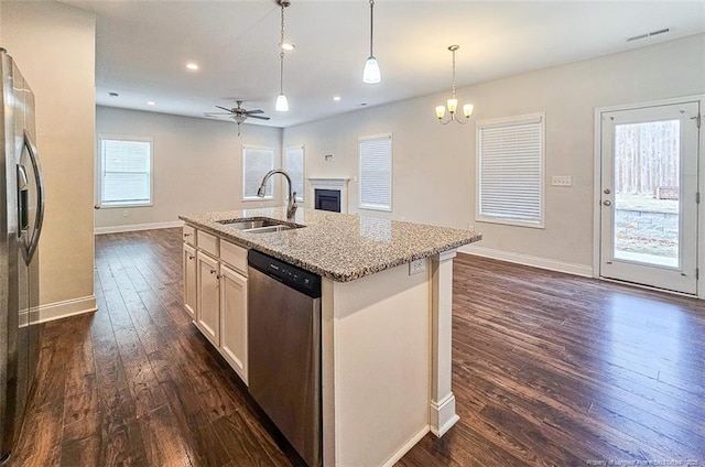 kitchen featuring black fridge with ice dispenser, open floor plan, stainless steel dishwasher, a fireplace, and a sink