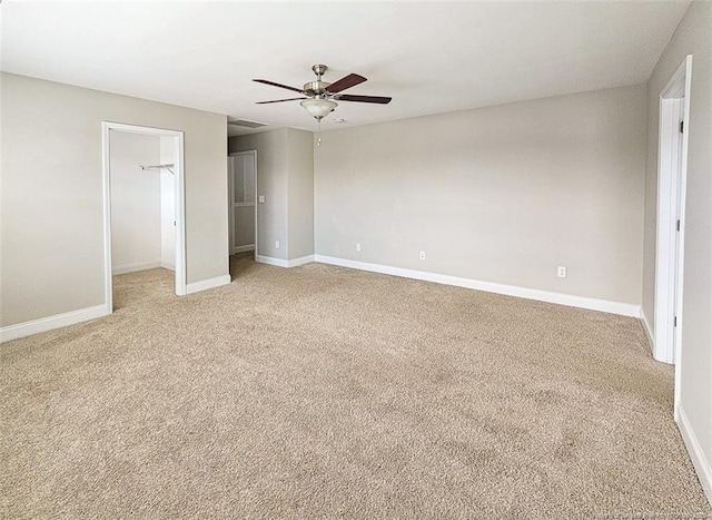 unfurnished bedroom featuring light carpet, baseboards, ceiling fan, a spacious closet, and a closet