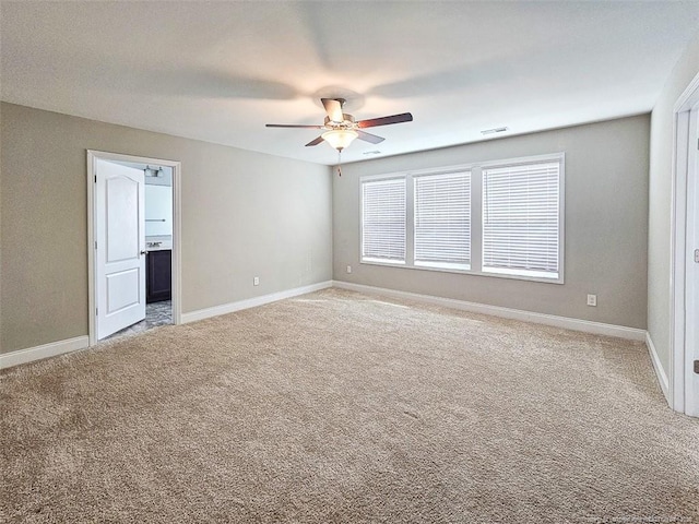 carpeted empty room featuring a ceiling fan, visible vents, and baseboards