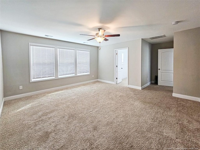 empty room with a ceiling fan, light colored carpet, visible vents, and baseboards