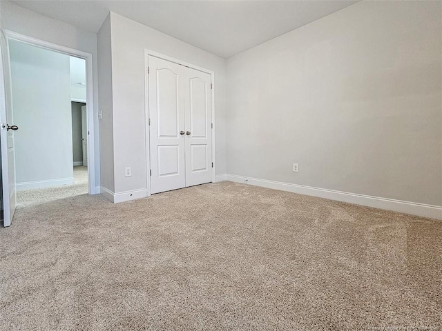 unfurnished bedroom featuring a closet, carpet, and baseboards