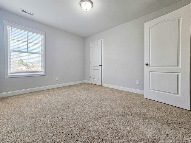 carpeted spare room with visible vents and baseboards