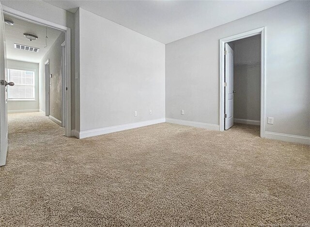 carpeted empty room with attic access, visible vents, and baseboards