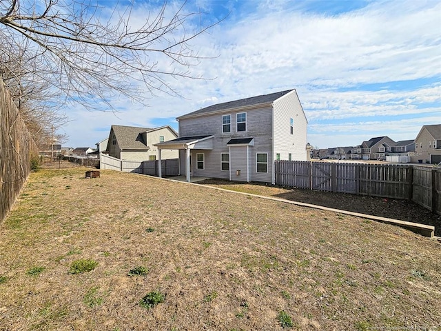 back of house featuring a yard, a fenced backyard, and a residential view