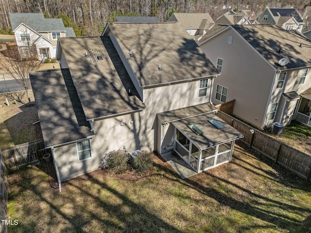 back of property featuring a yard, a shingled roof, a fenced backyard, and a tiled roof